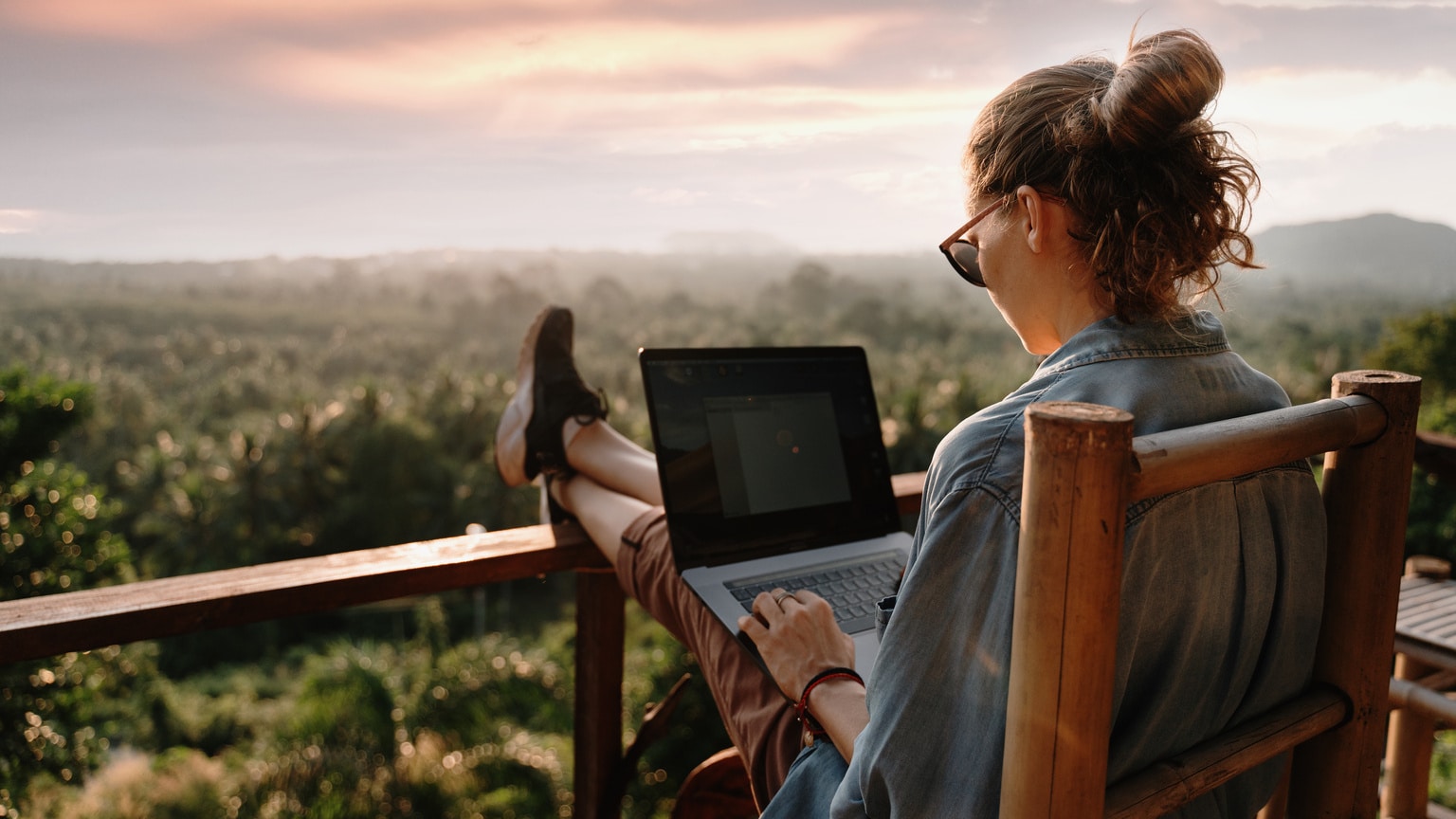 una imagen de un nómada digital trabajando en un país pintoresco durante una puesta de sol