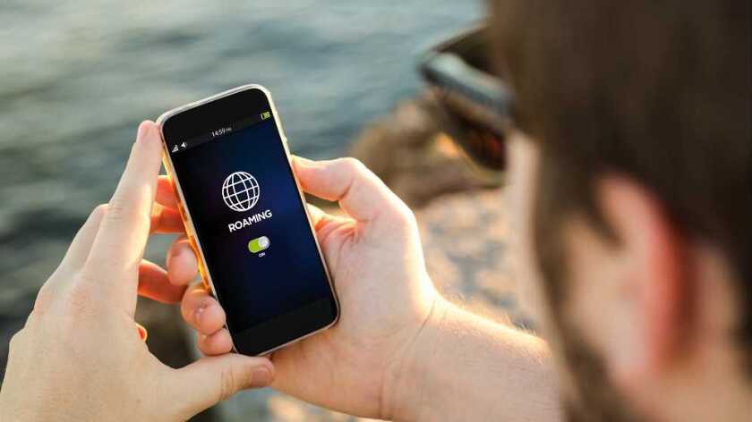 a man looking at his phone which has data roaming setting turned on