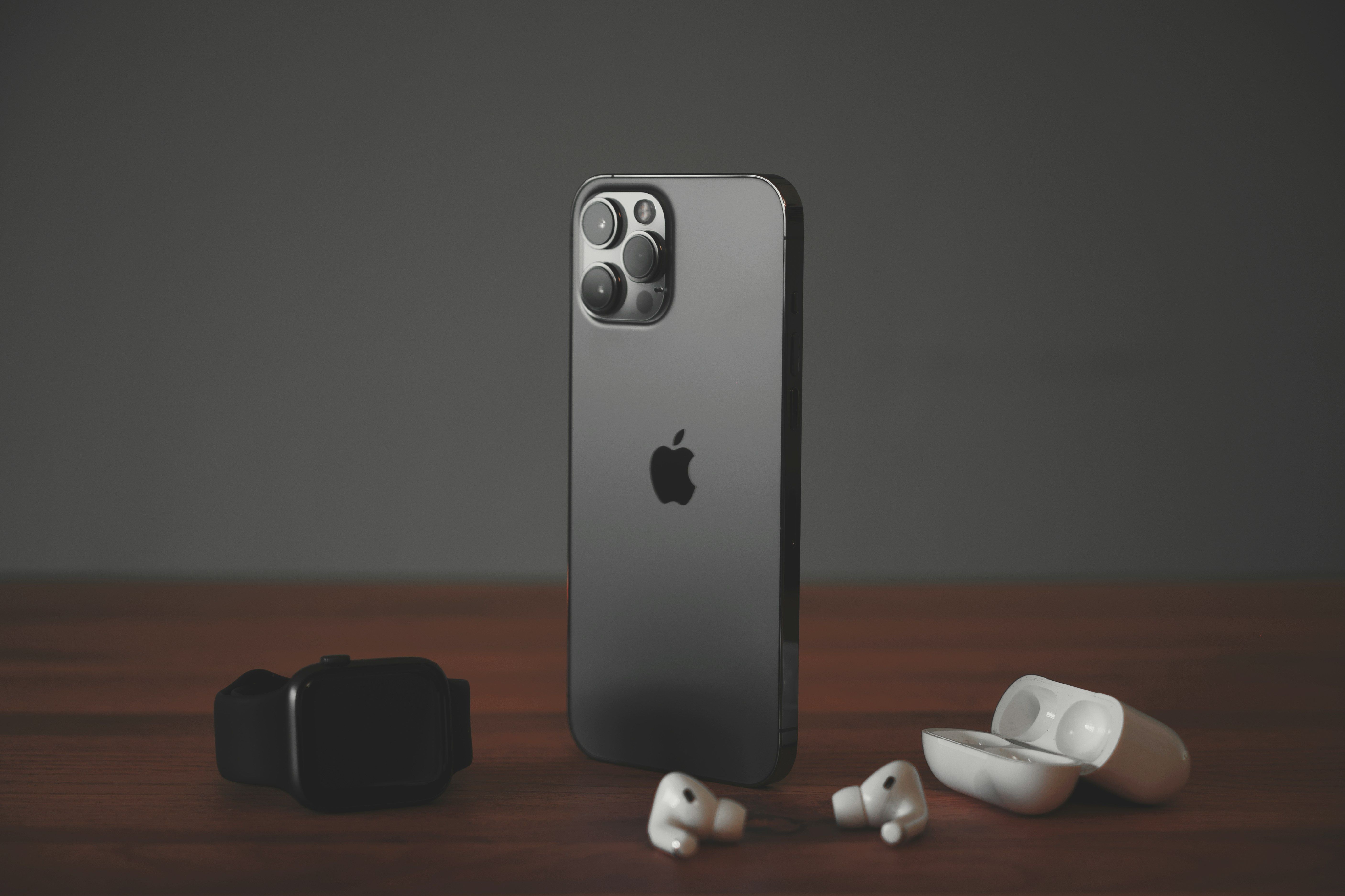 A black iPhone on a desk, surrounded by AirPods and an Apple Watch.