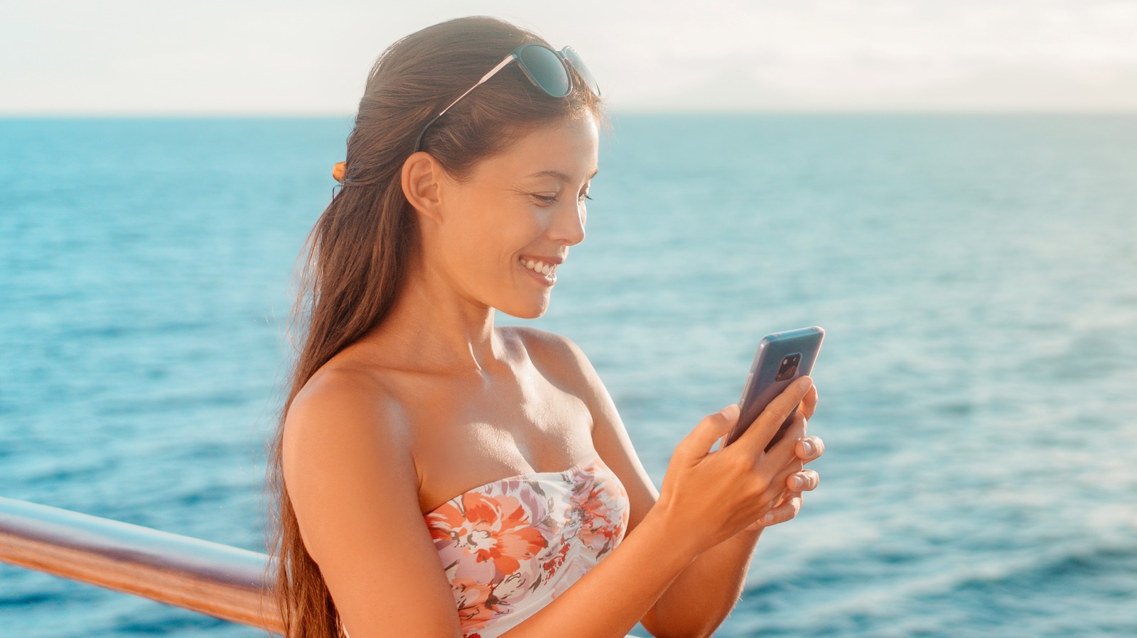woman on cruise ship using her phone and smiling