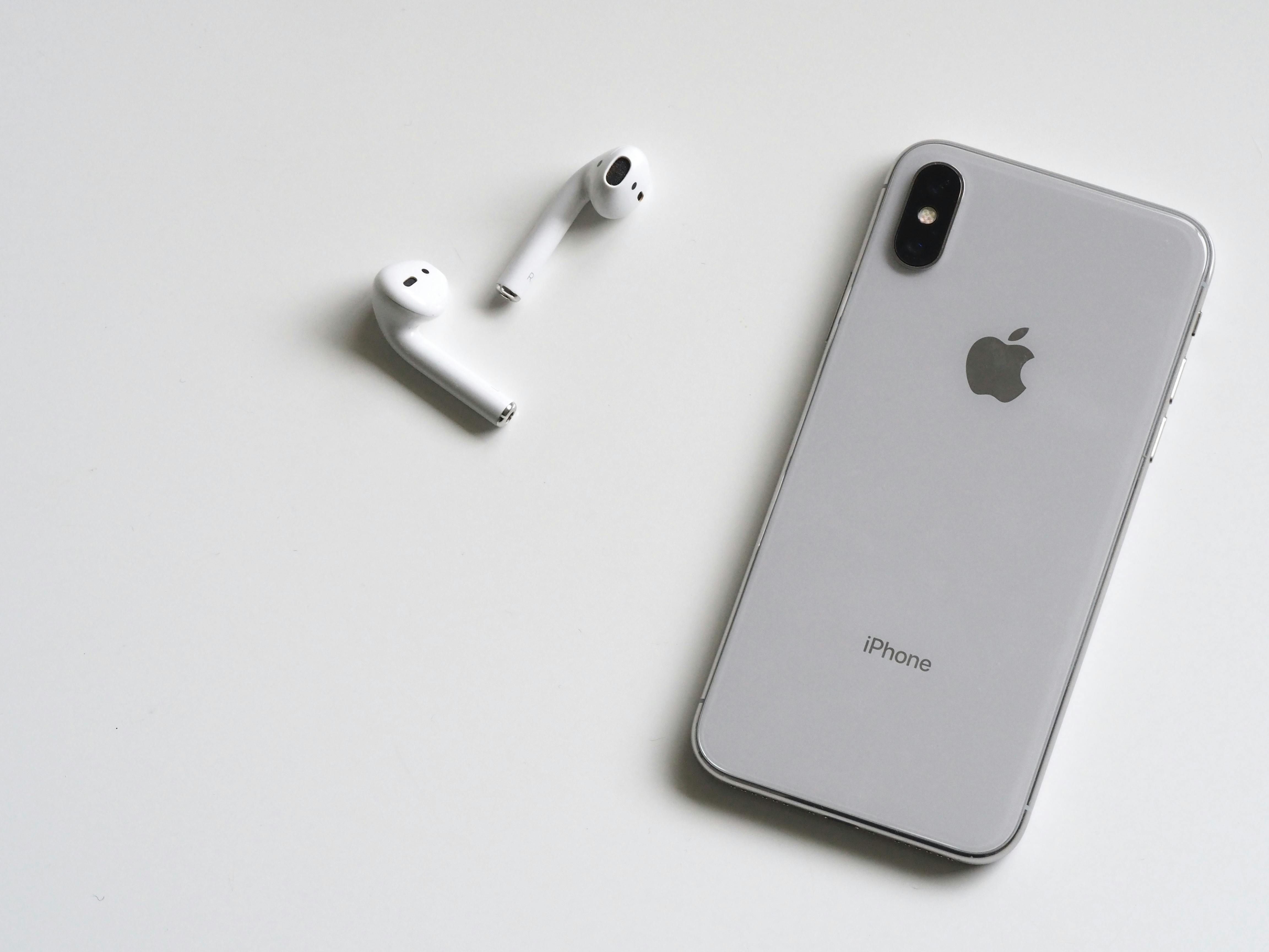 Ein iPhone mit Airpods daneben.